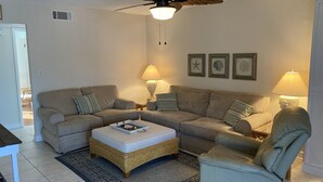 Una sala de estar con ventilador de techo, dos sofás, una mesa de centro y una silla.