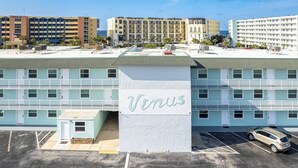 Un hôtel à plusieurs étages, nommé «Vénus», avec une façade bleu clair, de nombreux balcons et un parking.