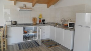A compact kitchen with white cabinets, a built-in microwave, and a stainless steel range hood. - Villa Luz II - between Serra and the Sea - Free Wifi (Santa Cruz)