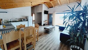 A spacious living area with a wooden ceiling, a dining table with chairs, a sofa, and a large potted plant. - Villa Luz II - between Serra and the Sea - Free Wifi (Santa Cruz)
