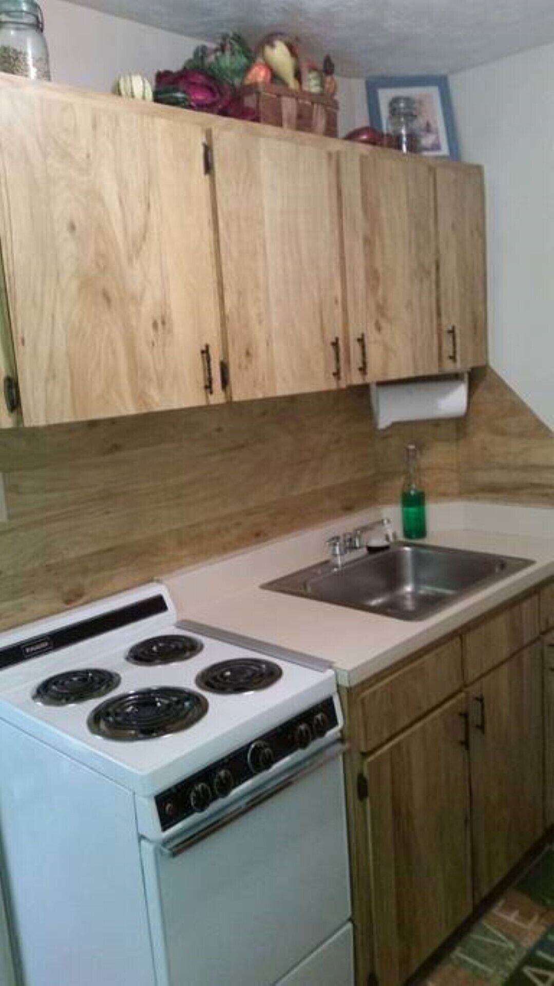 A kitchen with wooden cabinets, a white stove, and a sink.