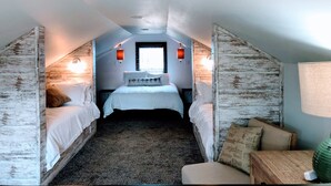 A bedroom with two beds, a window, and a small seating area.