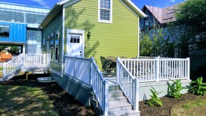 A green house with a white door and a small porch with a railing.