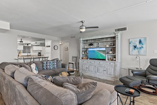 A modern living room with a gray sectional sofa, a leather recliner, and a glass coffee table.
