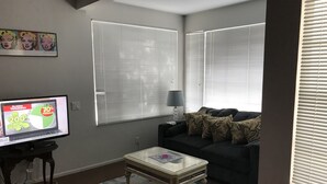 A living room with a television, a dark-colored sofa, and a coffee table. - Downtown-PALM-SPRINGS-Get-AWAY (Palm Springs)