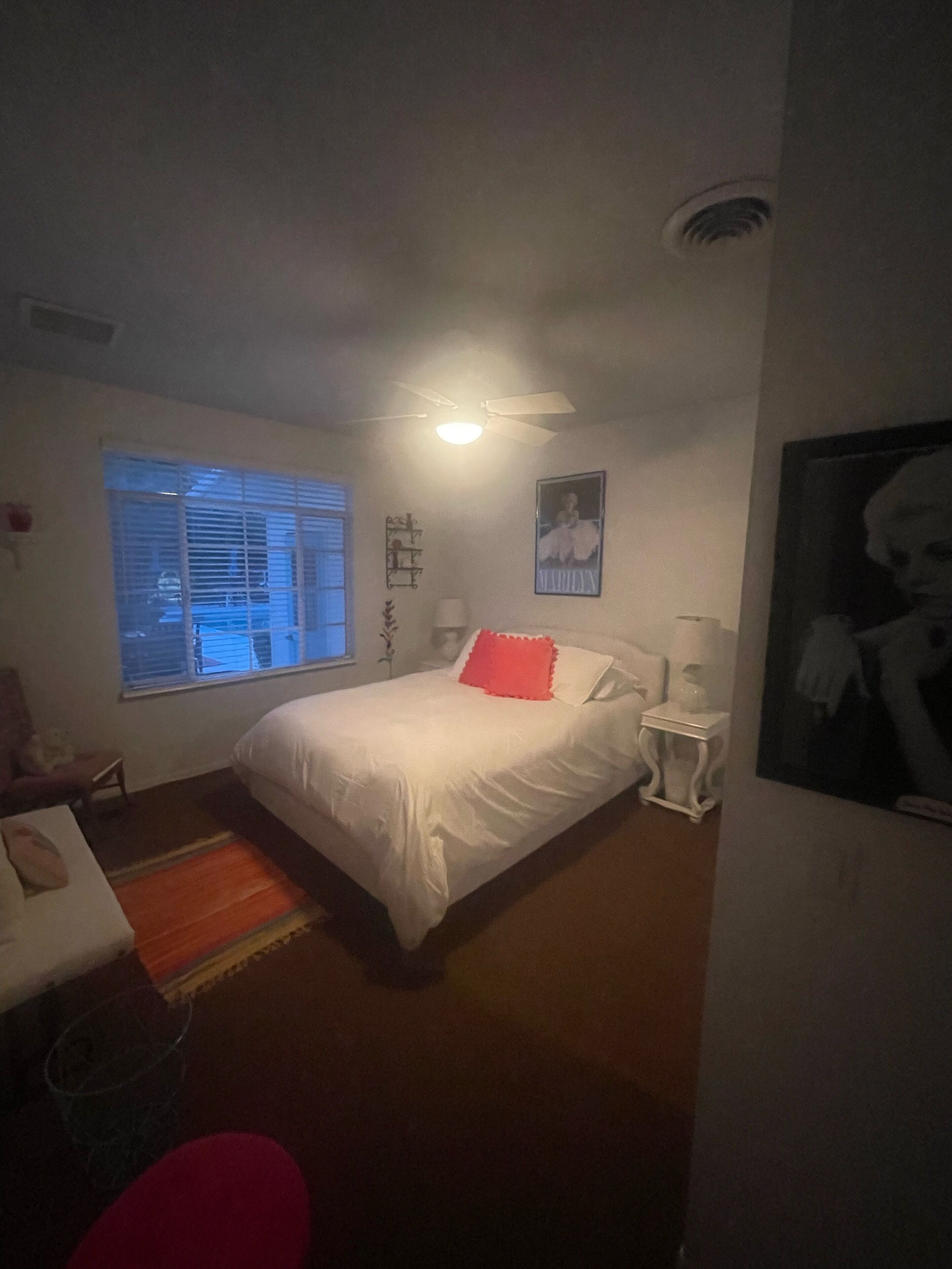 Ein Schlafzimmer mit Bett, Fenster, Deckenventilator und Nachttisch.