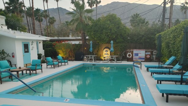 A pool area with lounge chairs, a barbecue grill, and a view of mountains. - Downtown-PALM-SPRINGS-Get-AWAY (Palm Springs)