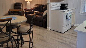 Une cuisine compacte avec un coin repas, comprenant une table avec des chaises, un ventilateur de plafond et un réfrigérateur.