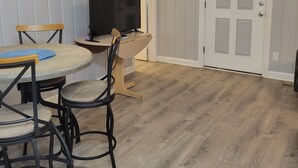 Un coin repas comprenant une table ronde, deux chaises, un téléviseur et une porte avec une fenêtre.