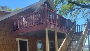 Une cabane avec une façade en bois, une véranda couverte, un escalier et une vue sur l’eau.