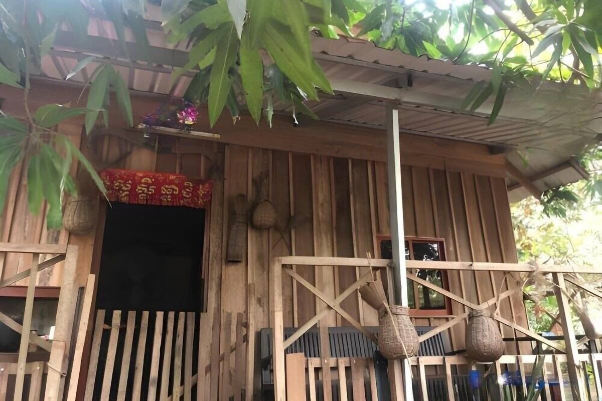 A rustic wooden structure with a slanted roof, a wooden gate, and a small porch area.