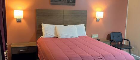 A hotel room with a large bed, two bedside lamps, a nightstand, a chair, and a painting on the wall.