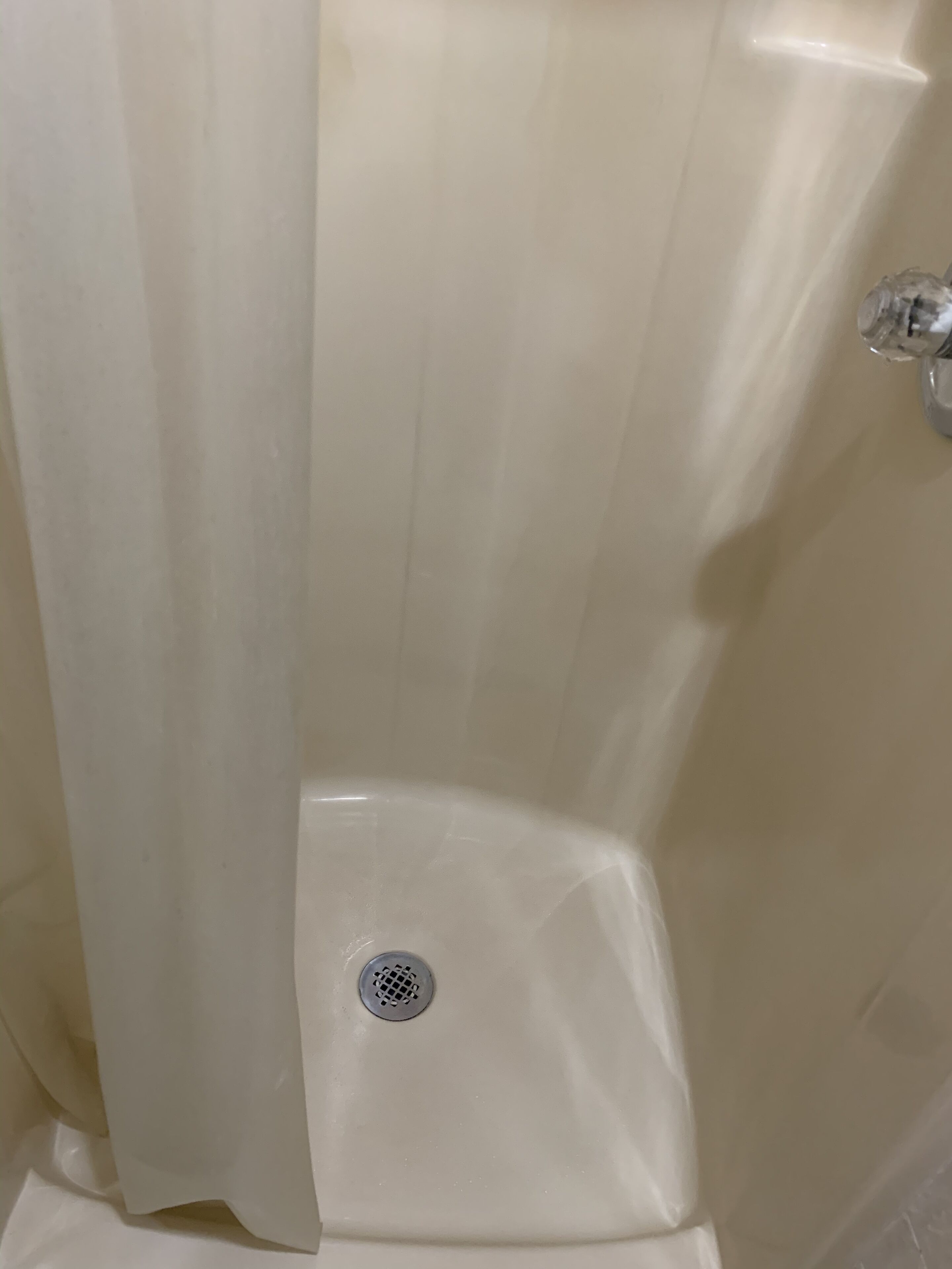 Un baño con ducha, desagüe y grifo.