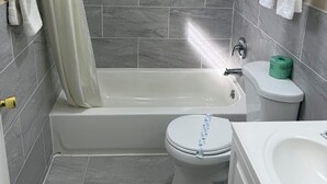 A bathroom with a bathtub, toilet, and sink. - Boone Trail Inn (Middlesboro)