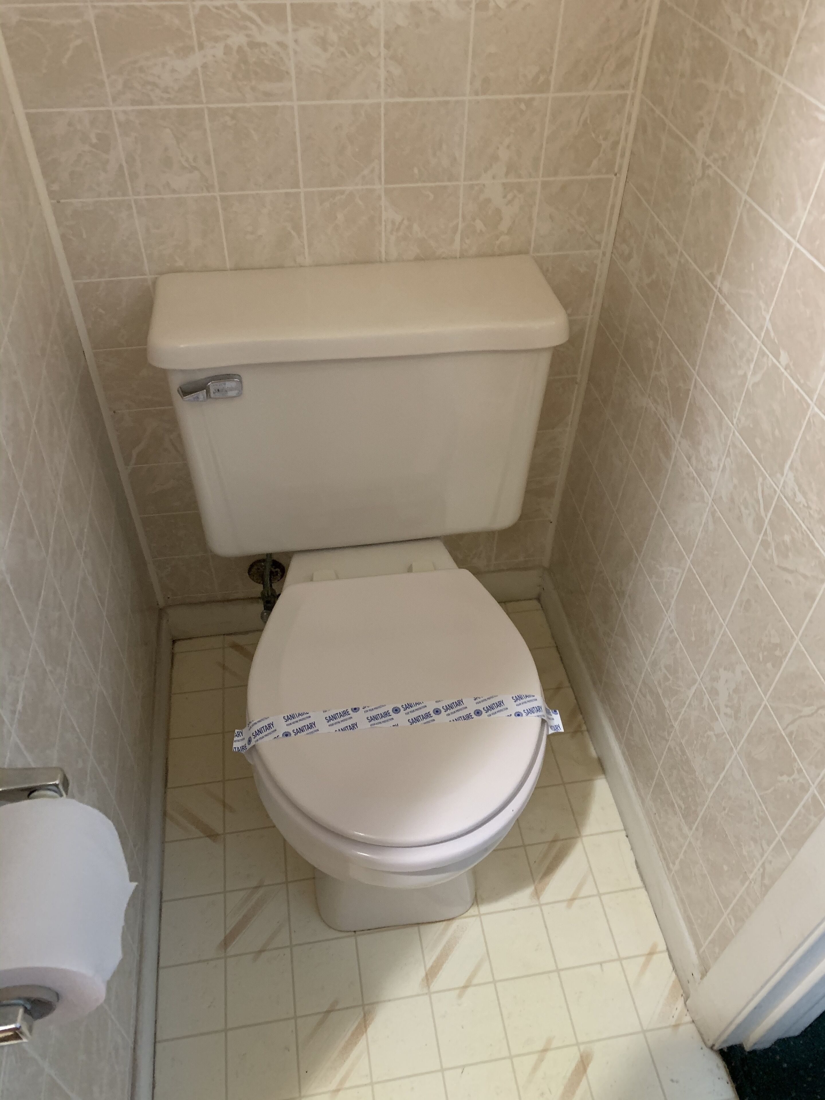 Un baño pequeño con inodoro, dispensador de papel higiénico e iluminación empotrada en la pared.