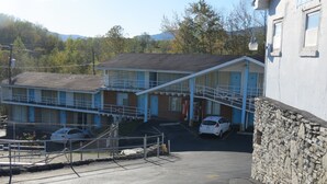 A motel with a two-story structure, a parking lot, and a stone wall. - Boone Trail Inn (Middlesboro)