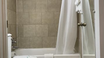 A bathroom with a toilet, bathtub, and shower curtain.