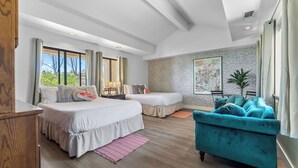 Ein Schlafzimmer mit zwei Betten, einem türkisfarbenen Sofa und einer Steinwand.