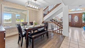 Ein Essbereich mit Holztisch, Stühlen und einer Bank. Eine Treppe mit Holzwandungen führt zu einer erhöhten Ebene.