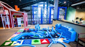 A play area with a climbing wall, a small building with a sign, and a play mat with various shapes. - Smuggler's Notch Resort by Resort Stay (Jeffersonville)