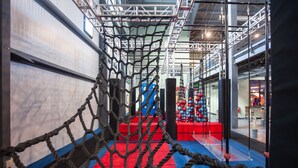 An indoor obstacle course with rope nets, red and blue mats, and a blue and red climbing wall. - Smuggler's Notch Resort by Resort Stay (Jeffersonville)