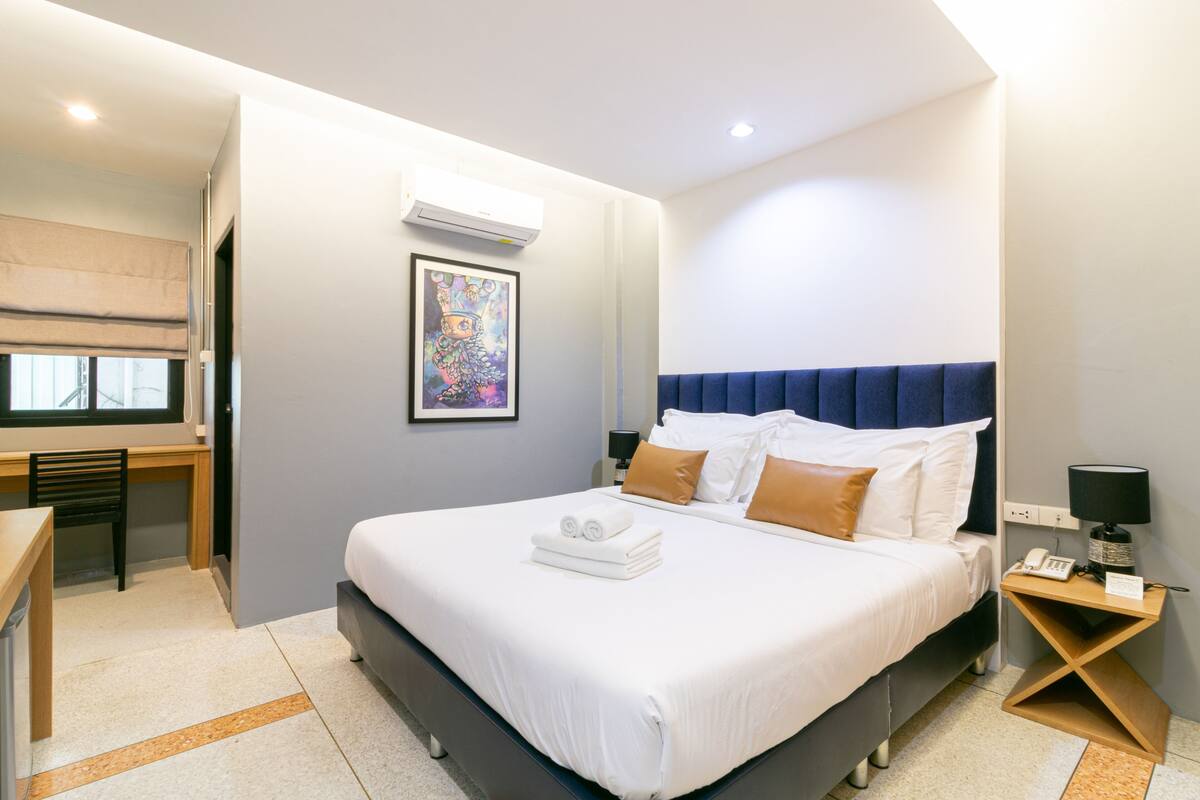 A modern hotel room with a large bed, a desk, and a chair.