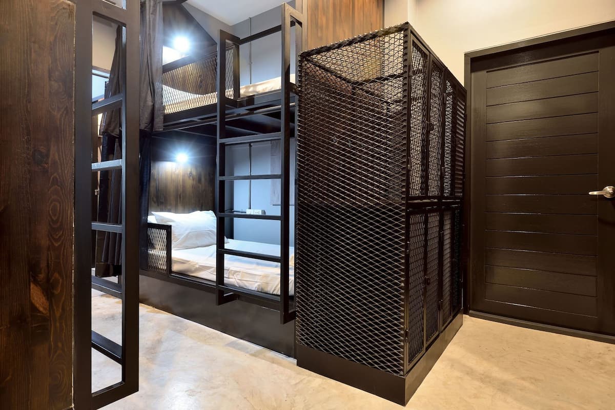 A room with a bunk bed, a metal partition, and a door.