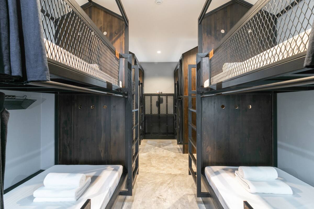 A hotel room with bunk beds, a wooden floor, and a small seating area.