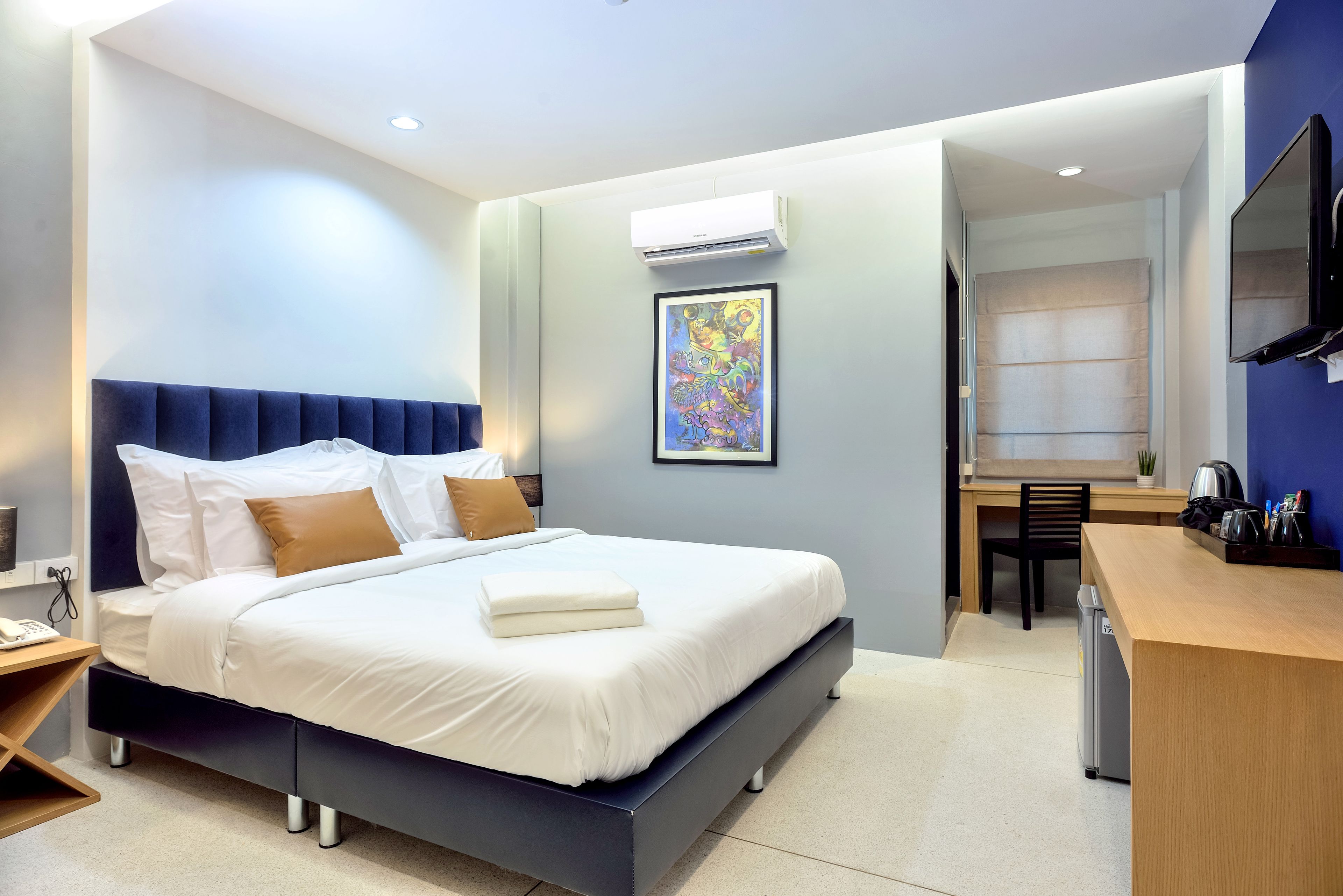 Una habitación de hotel moderna con una cama grande, un escritorio y un televisor.