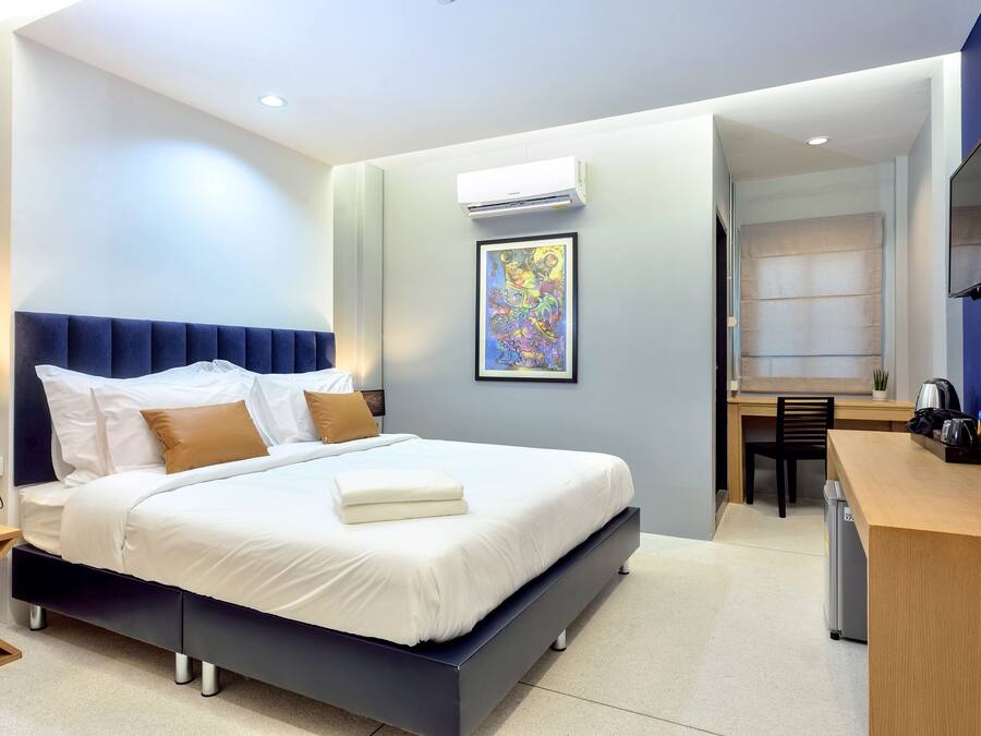 Una habitación de hotel moderna con una cama grande, un escritorio y un televisor.