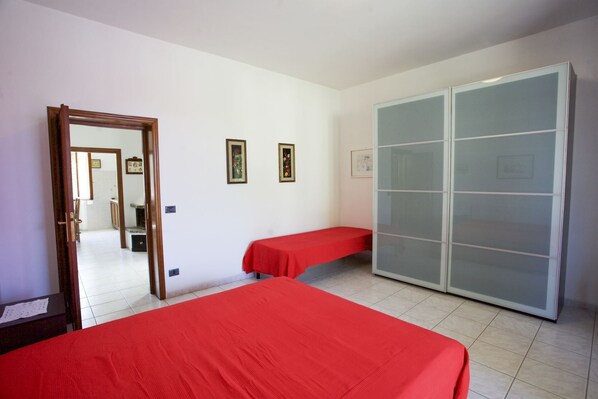Une chambre avec deux lits, une armoire et une porte donnant sur une autre pièce.