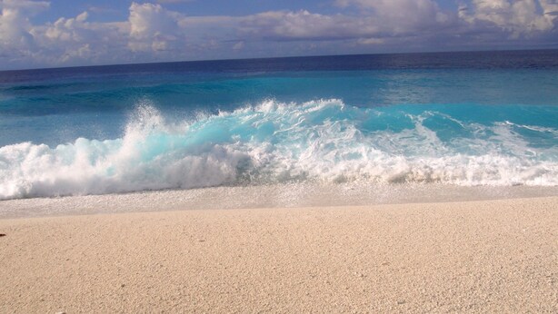 A beach with clear turquoise water and white waves.