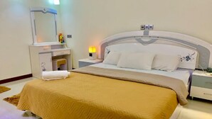A hotel room with a large bed, a bedside table, a nightstand, a mirror, and a lamp.