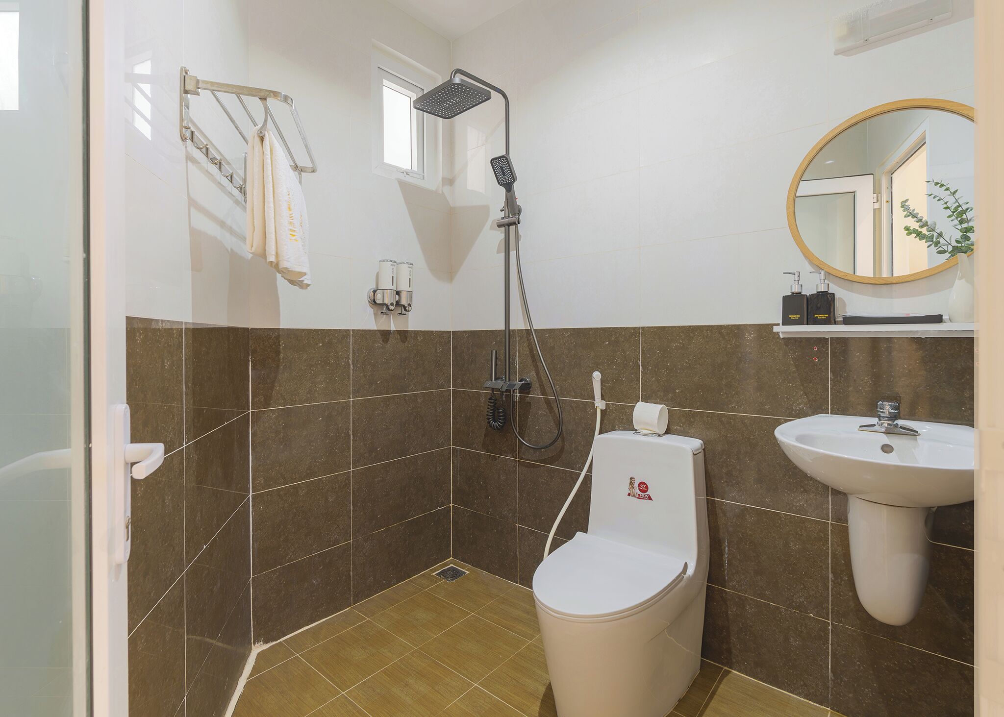 A bathroom with a shower, toilet, sink, and a mirror.