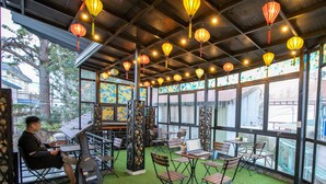 An indoor dining area with tables and chairs, large windows, and hanging lanterns. - Green Meadow Central Đà Lạt - O'TEL (Xuan Huong - Da Lat)