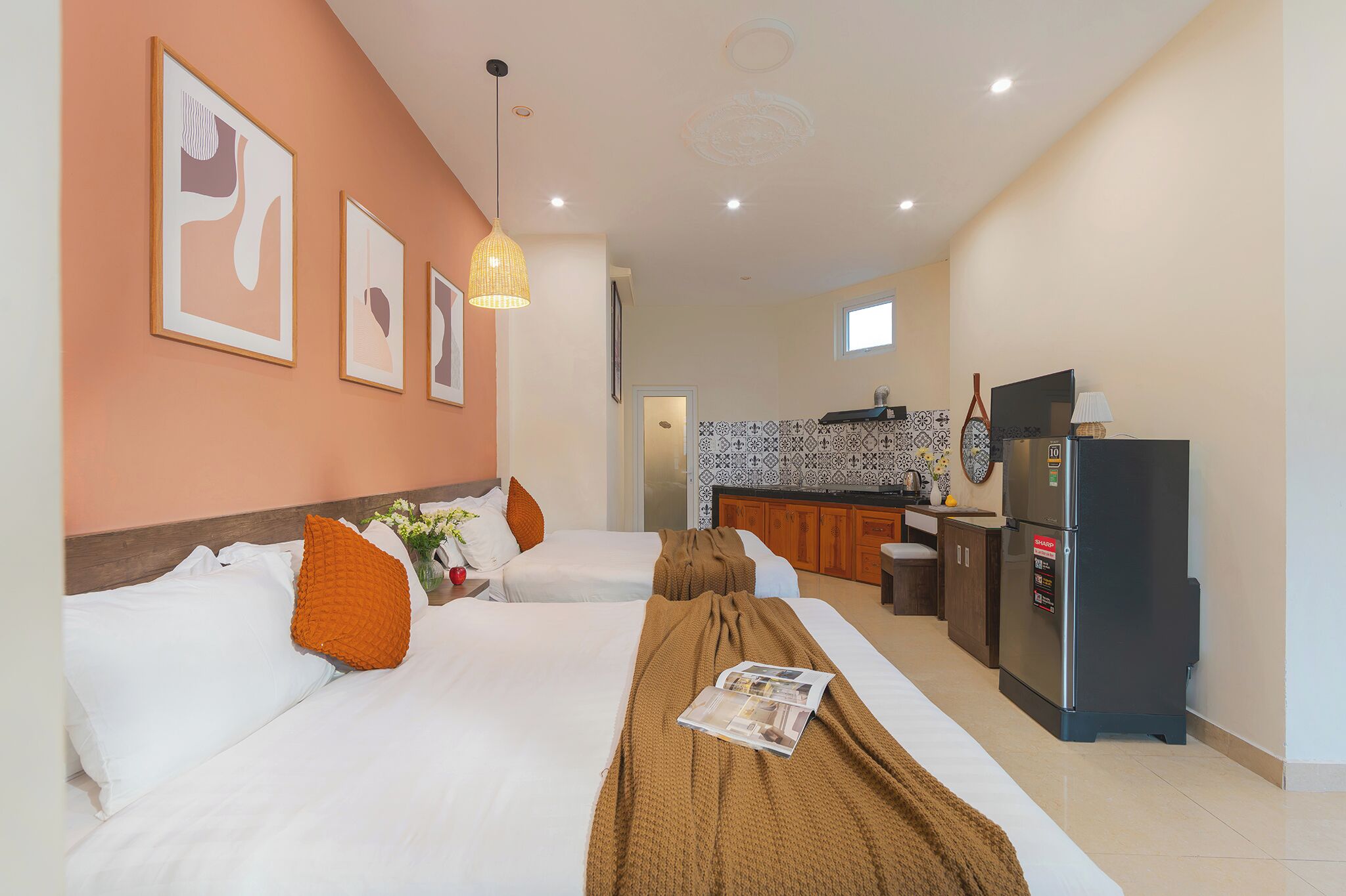 A hotel room with two beds, a kitchenette, and a refrigerator.