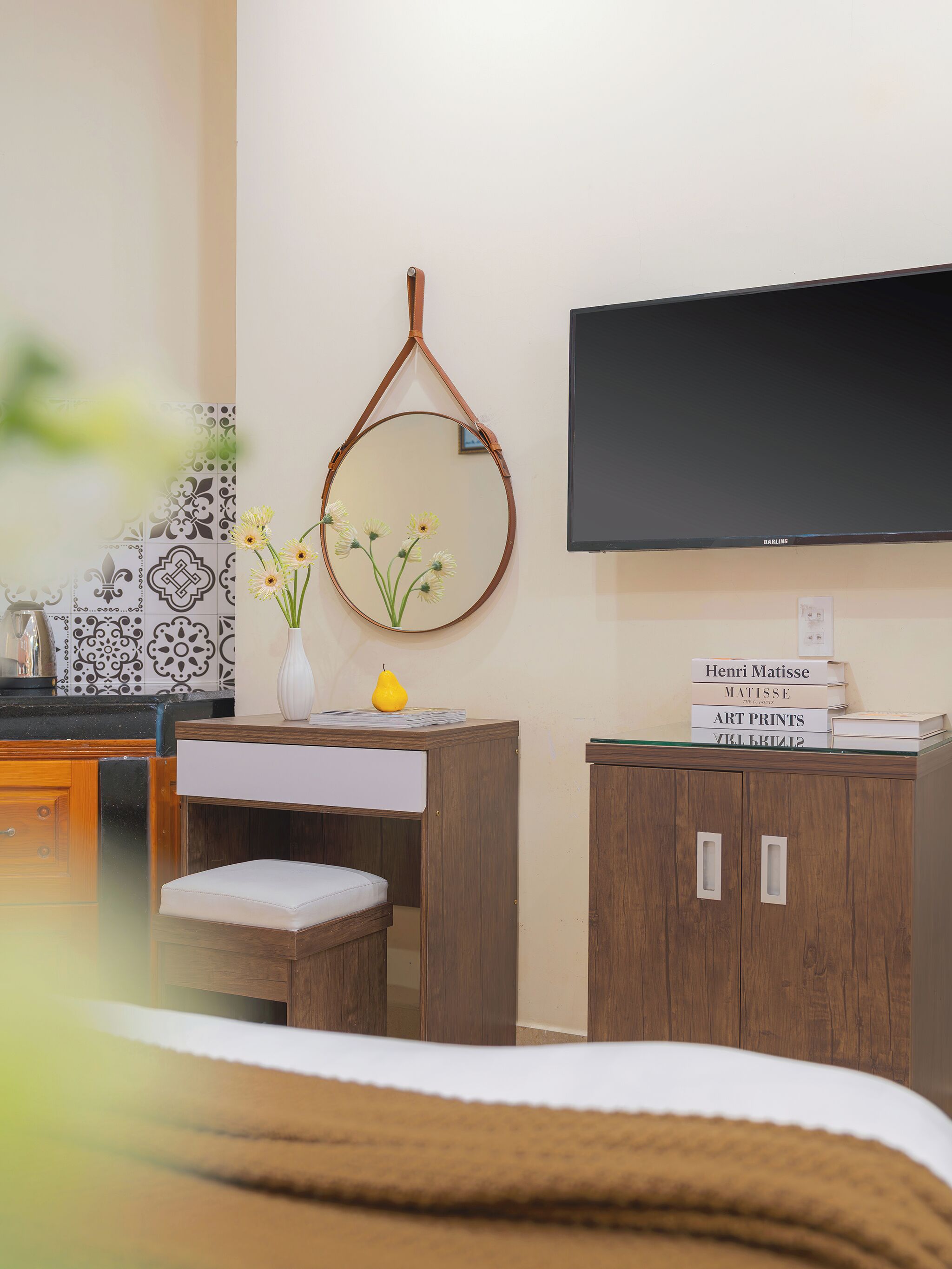 A bedroom with a bed, a desk with a chair, a mirror, a television, and a cabinet.