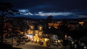 A hotel with multiple stories, a balcony, and a view of the surrounding town at night. - Green Meadow Central Đà Lạt - O'TEL (Xuan Huong - Da Lat)