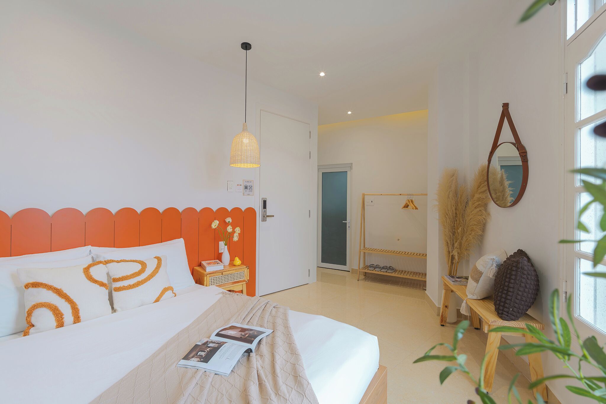 A modern bedroom with a bed, a bedside table with a lamp, and a window with a view.