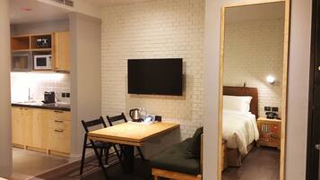 A compact hotel room with a kitchenette, a dining area, and a bed.