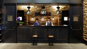 A modern bar area with a wooden wall, two bar stools, and overhead lighting. - Just Sleep Sanchong (New Taipei City)
