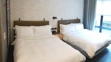 Two twin beds with white linens, a brick-patterned wall, and a window with curtains.