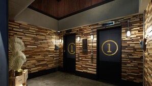 A hallway with wooden panel walls, two doors marked with a number, and a plant on the left. - Just Sleep Sanchong (New Taipei City)