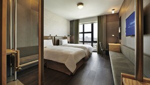 A hotel room with a large bed, a desk, a chair, a TV, and a window with a city view. - Just Sleep Sanchong (New Taipei City)