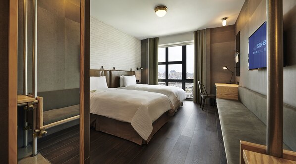 A hotel room with a large bed, a desk, a chair, a TV, and a window with a city view. - Just Sleep Sanchong (New Taipei City)