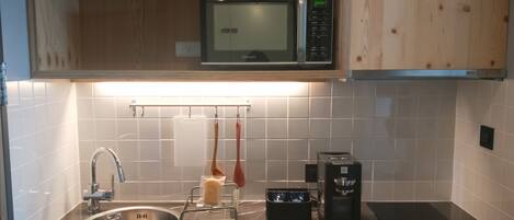 A kitchen with a sink, a microwave, a coffee maker, and a toaster.