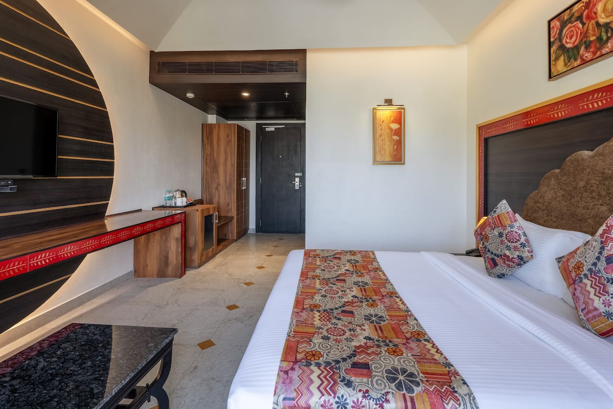 A hotel room with a bed, a TV, a desk, and a wardrobe.