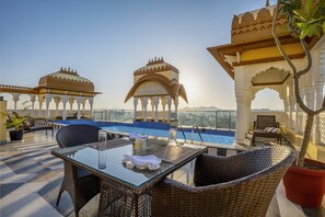 A rooftop terrace with a pool, wicker furniture, and ornate architectural details. - Sterling Balicha Udaipur (Udaipur)
