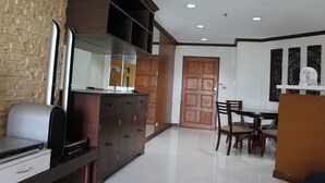 A modern kitchen with a built-in stove, a dining area with a table and chairs, and a wooden door. - Ploenchit Superb Location, 86sqm, nearby Bumrungrad Hospital - minimum 30 days (Khwaeng Makkasan)