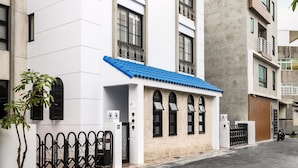 A modern building with a white facade, blue roof, and arched windows. - Madam's mansion Homestay (Taitung)